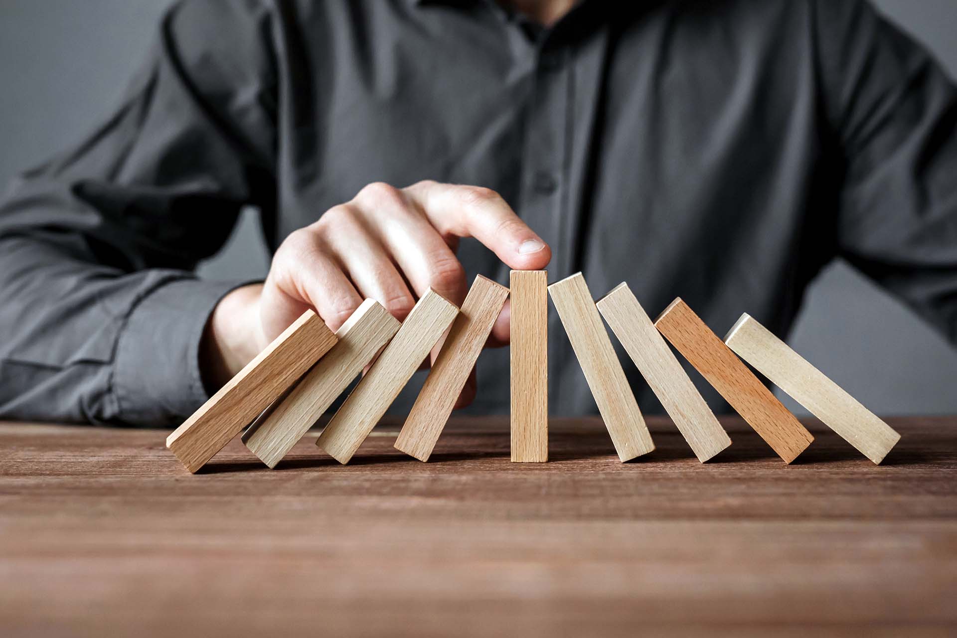 image of dominos falling on a table with a central domino stopping the chain