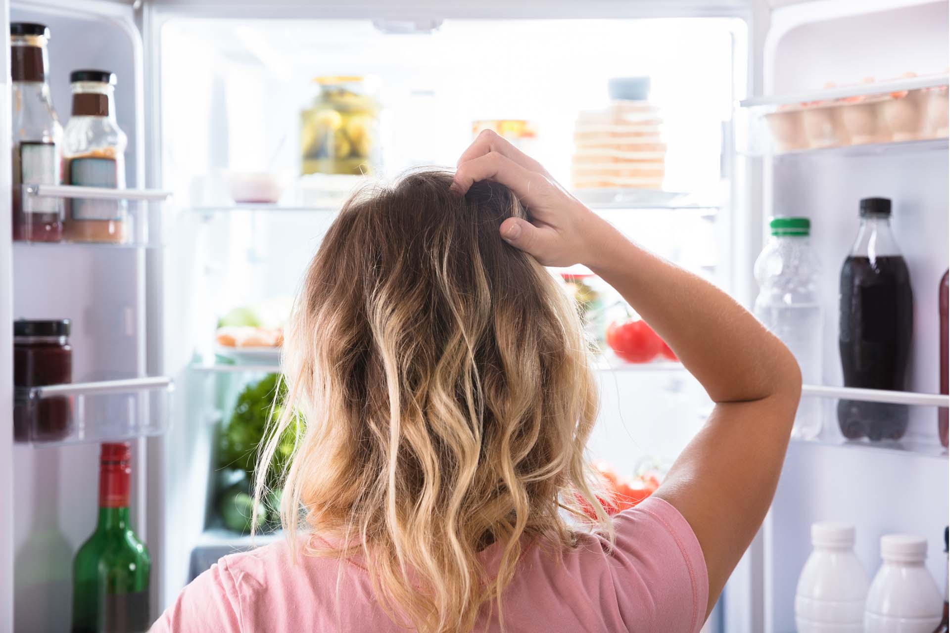 image of woman looking into fridge deciding what to eat