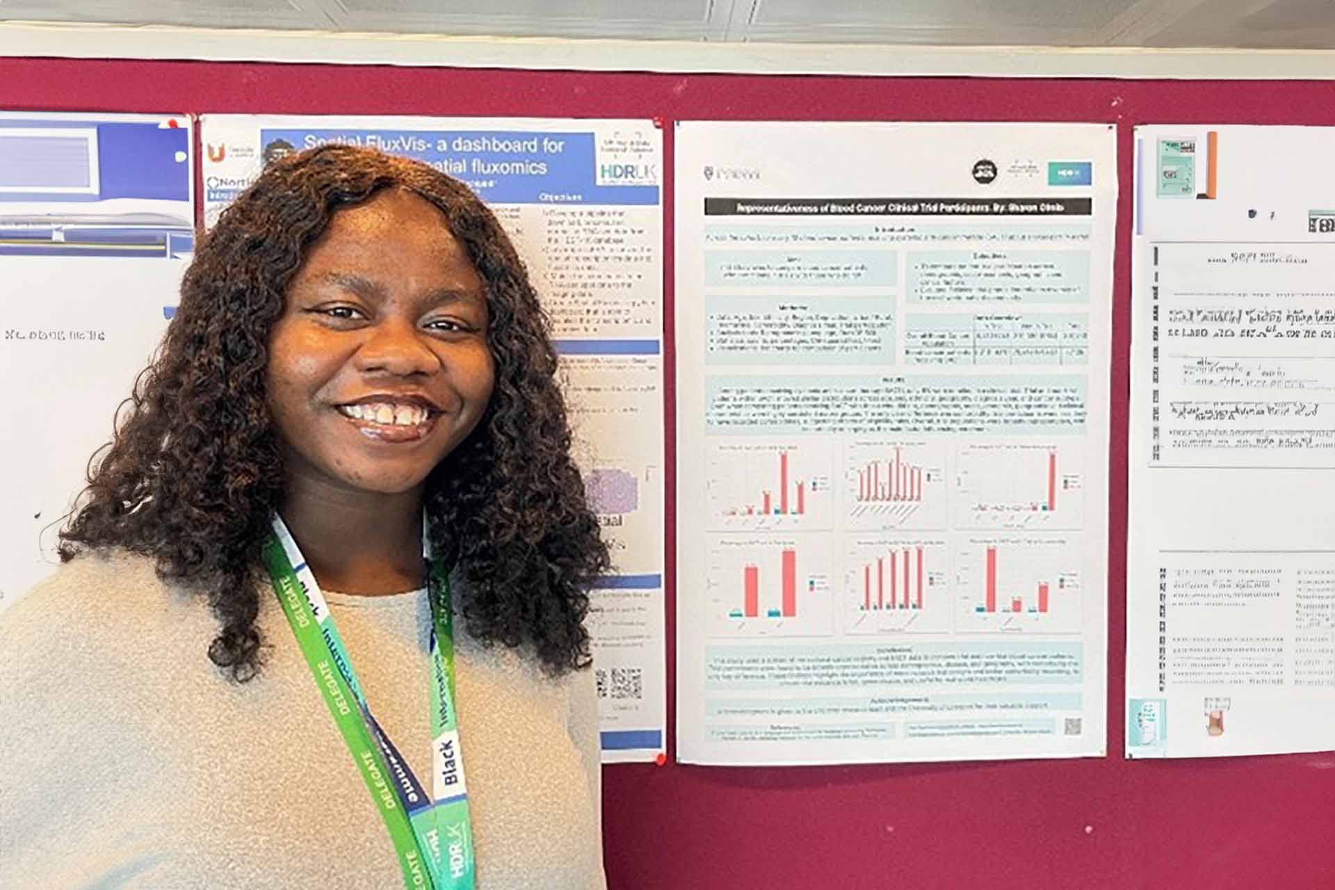 Student Sharon Okolo standing in front of poster at event