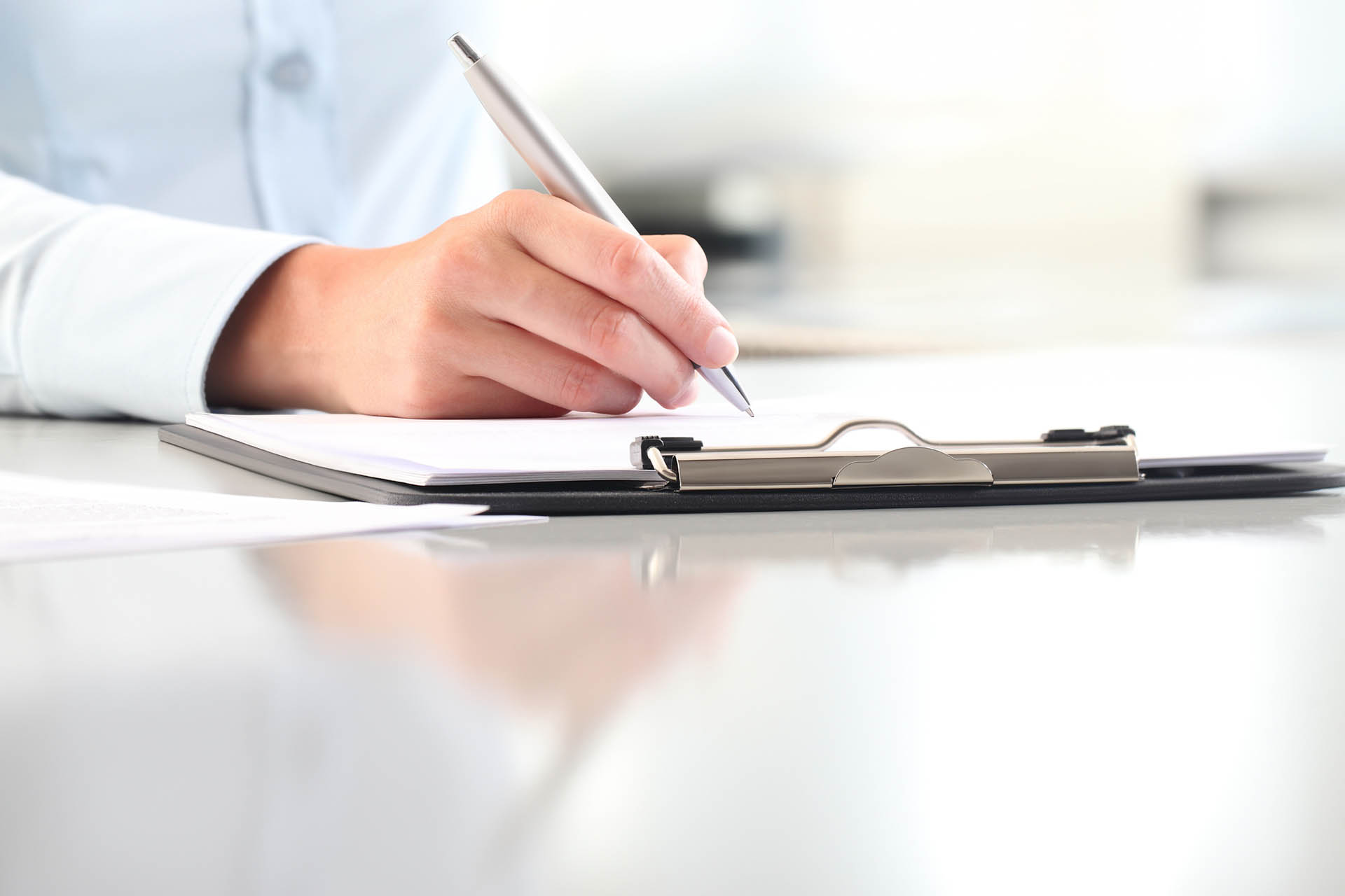 Woman sitting at a desk writing on a clipboard