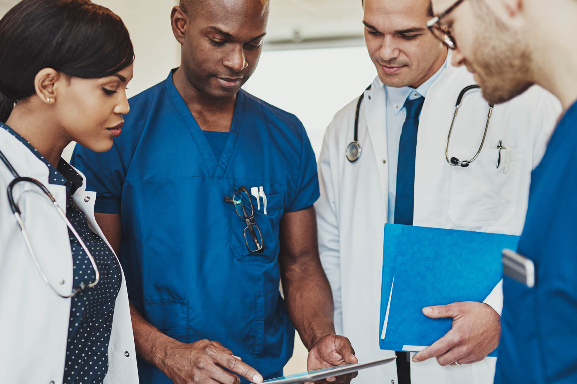 Group of doctors standing talking and looking at an iPad