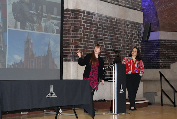 Two female data scientists presenting their public engagement activity on stage at a showcase event