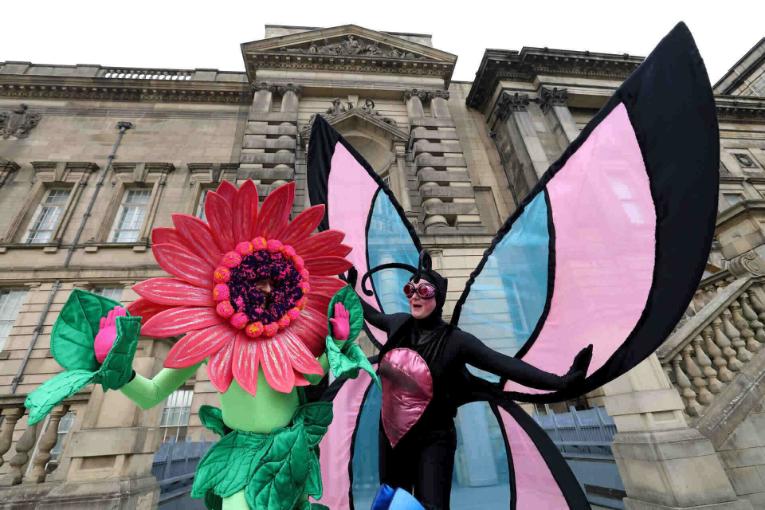 A Meet the Scientist volunteer dressed as a butterfly moving towards a flower