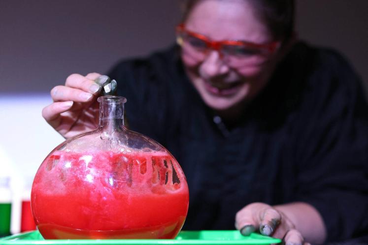 A female volunteer pouring a solution into a large glass bottle