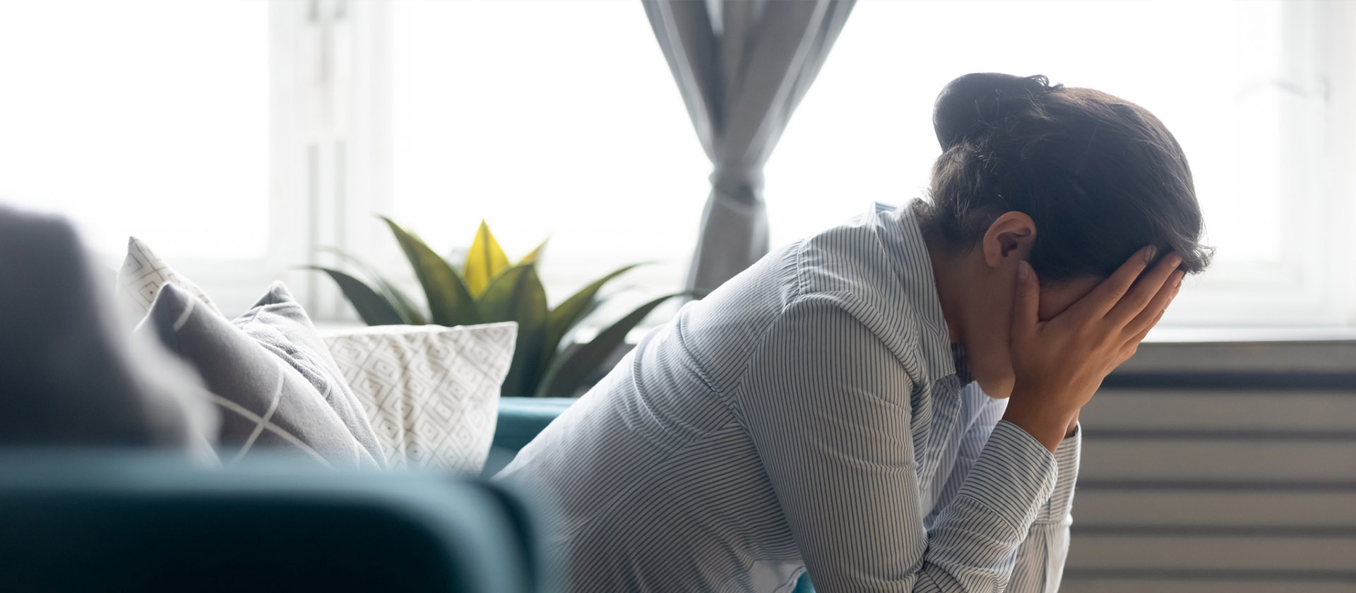 Woman sitting with her head in her hands, in pain