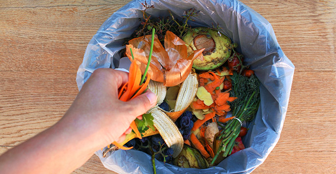 Person putting food waste in a bin