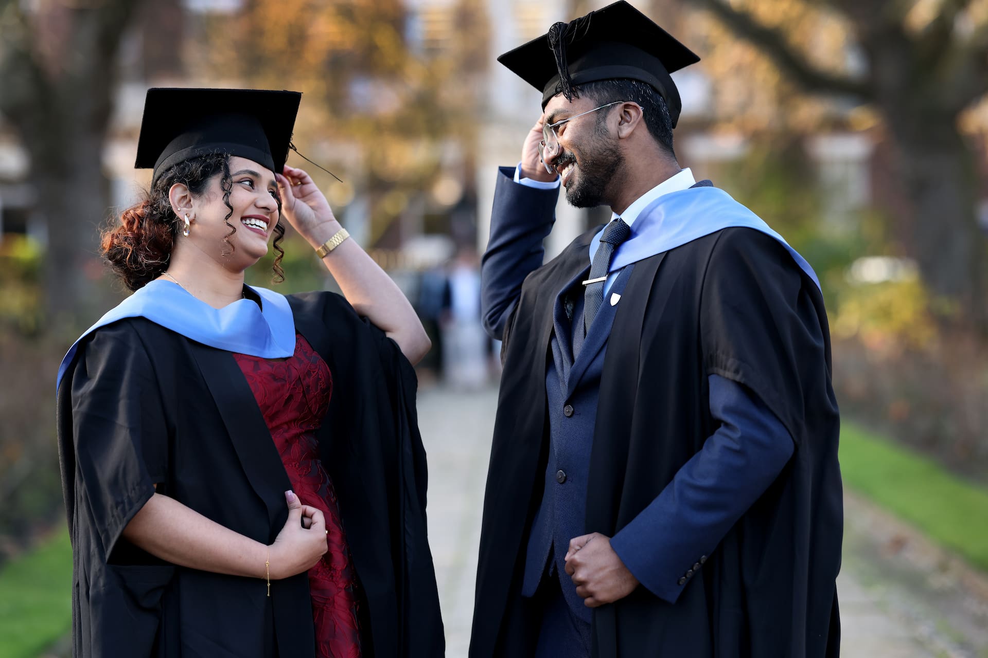 Two students on graduation day touching their caps