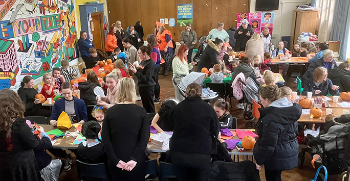 Hall full of parents and children doing crafts at a Halloween themed