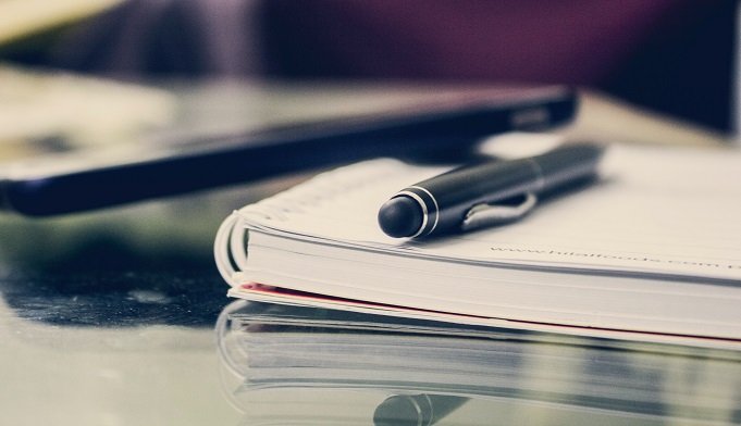 a pen on top of a blank notebook 