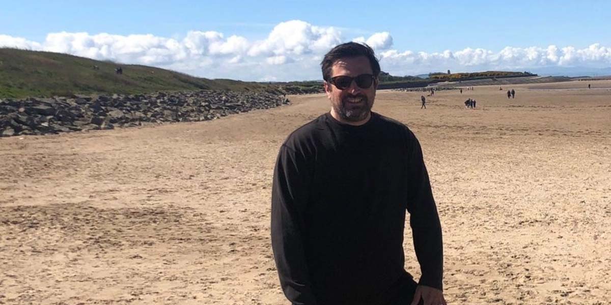 Jon Hogg standing against a beach backdrop