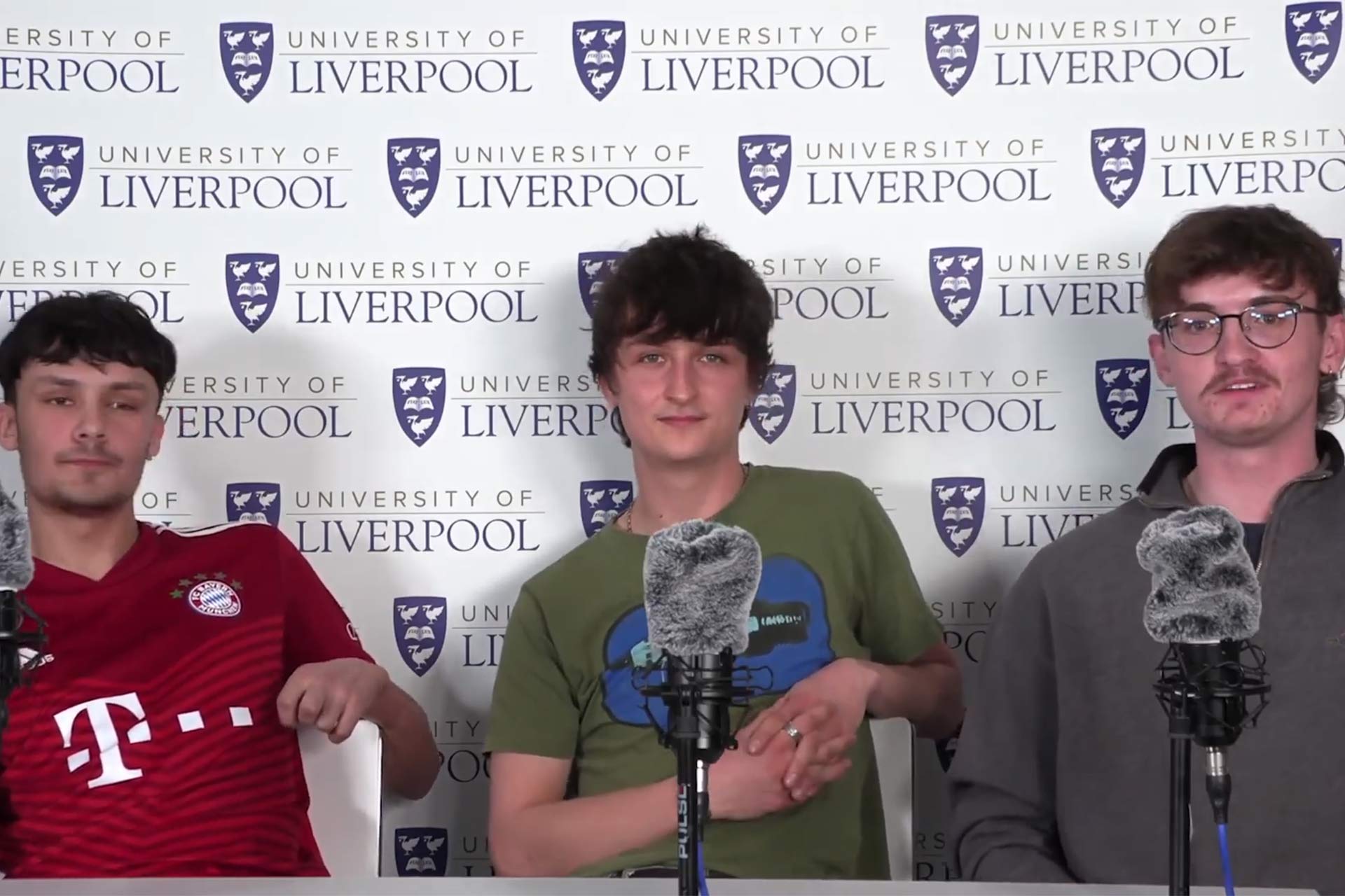 Three students sat in front of microphones talking to the camera.