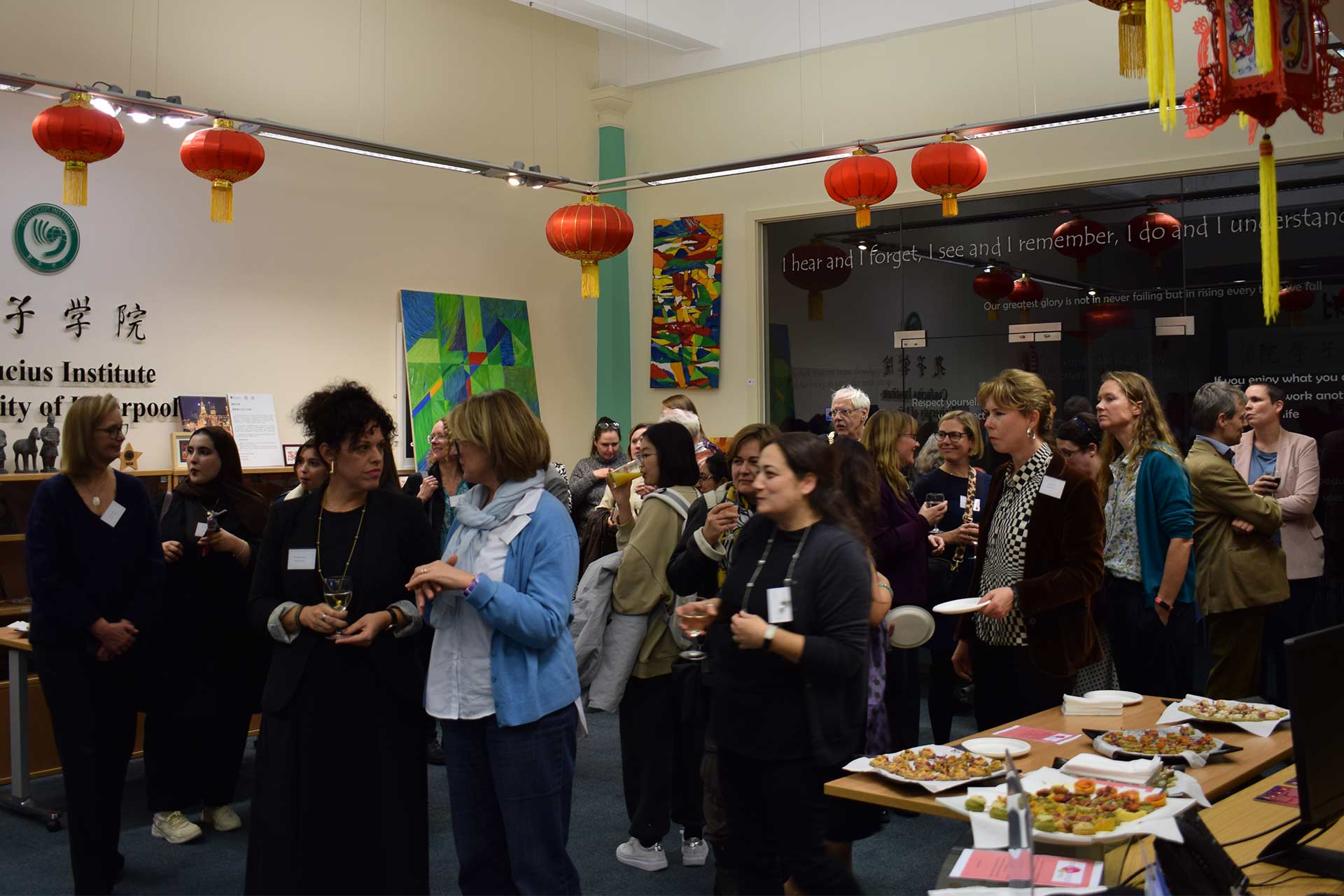 A group of people gathered together eating and drinking at an event inside.