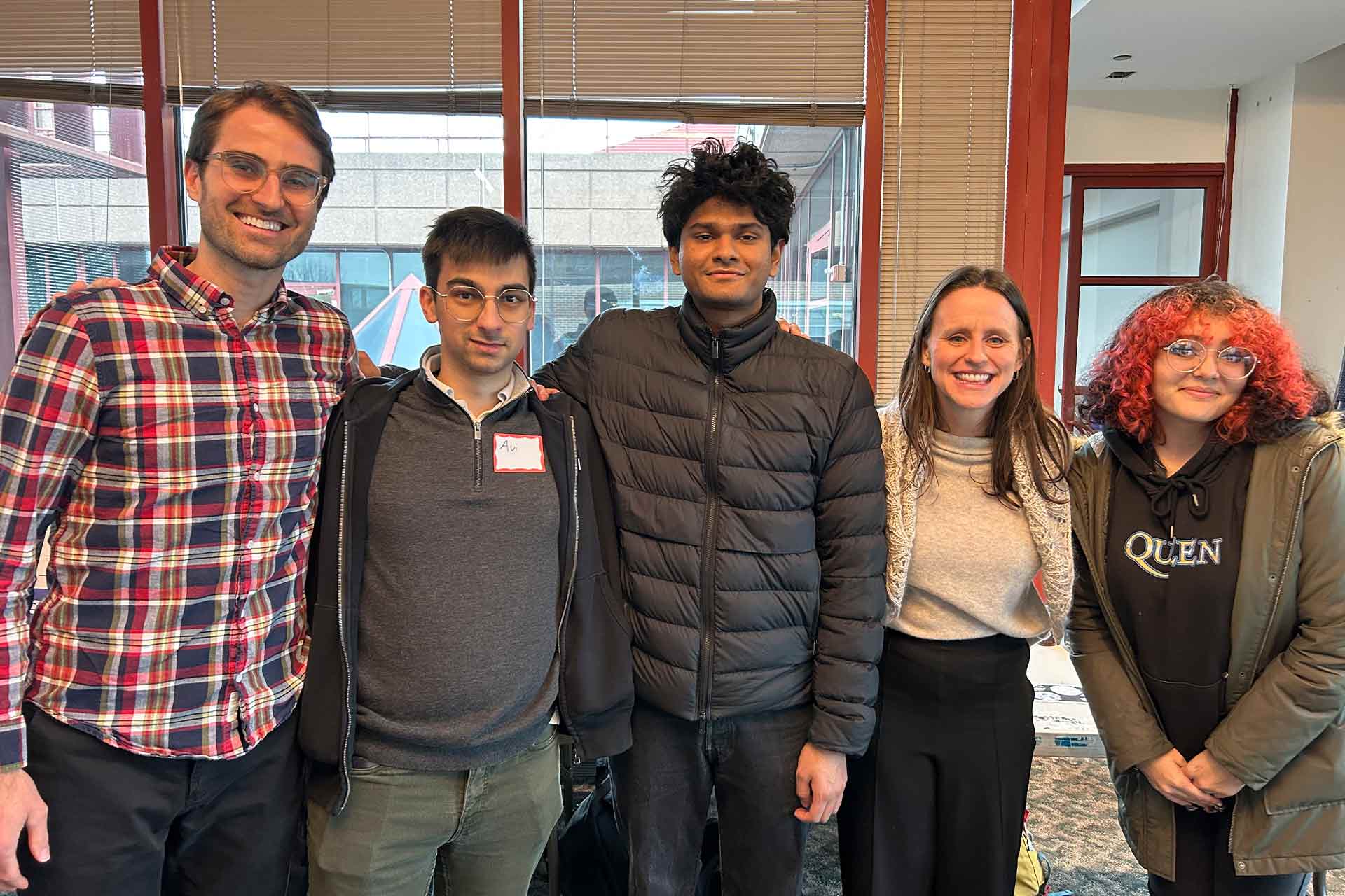 Five people standing in a line and smiling
