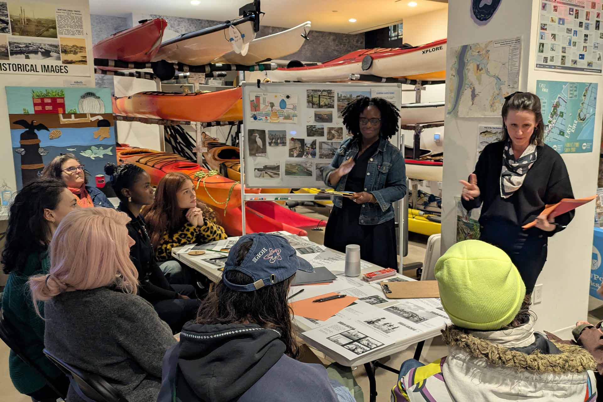Two women talking to a table of people at an event.
