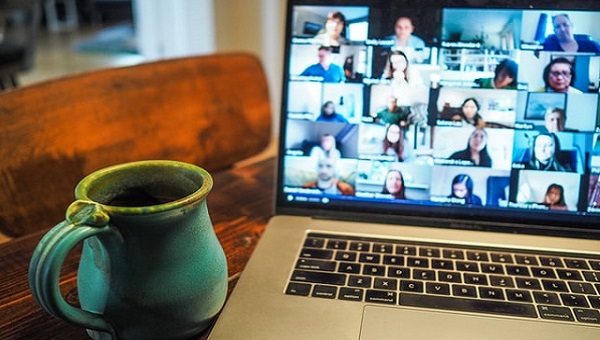macbook pro displaying a group of people on a Zoom call with a cup to the side of the screen