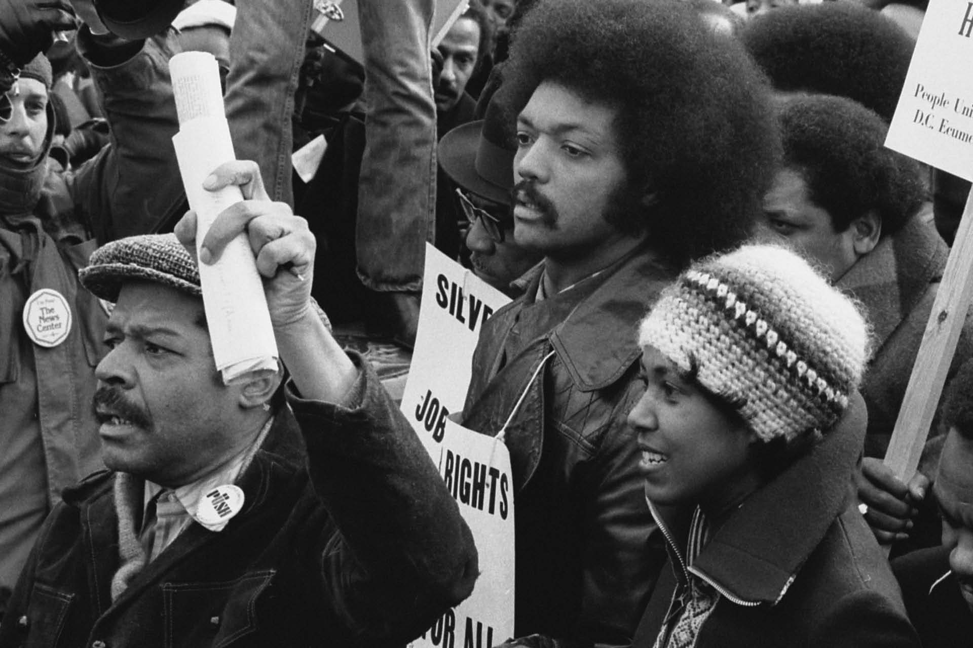 A black and white image of people protesting and holding signs.