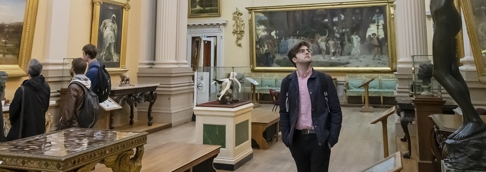 Student looking up at statue in gallery.