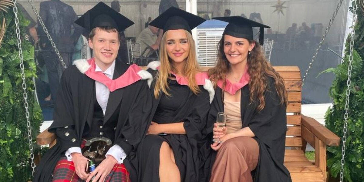 Three students sitting on a bench at the graduations