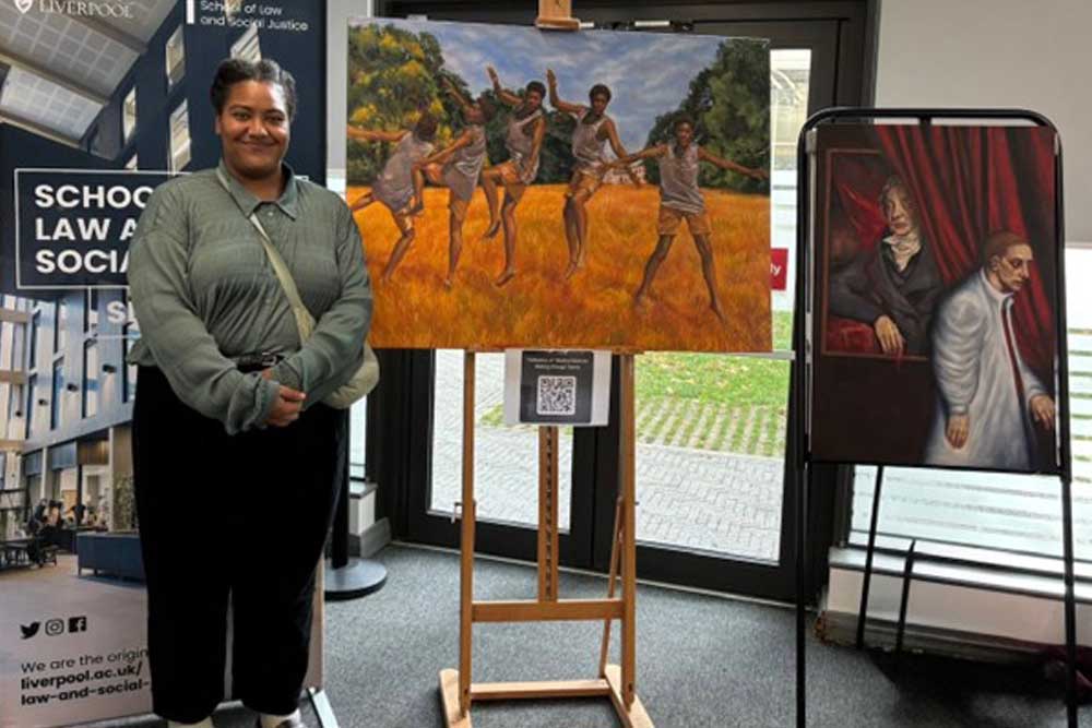 Anna-Louise Loy standing next to her paintings
