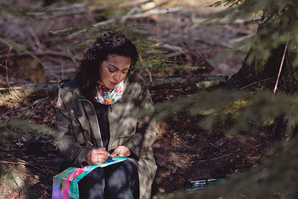 Bryony Ella sitting in woodland sketching