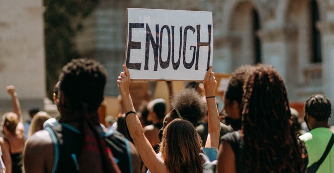 A woman holding a sign that reads 'Enough'