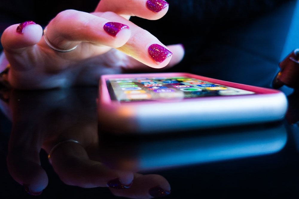 A woman's hand poised over a smartphone