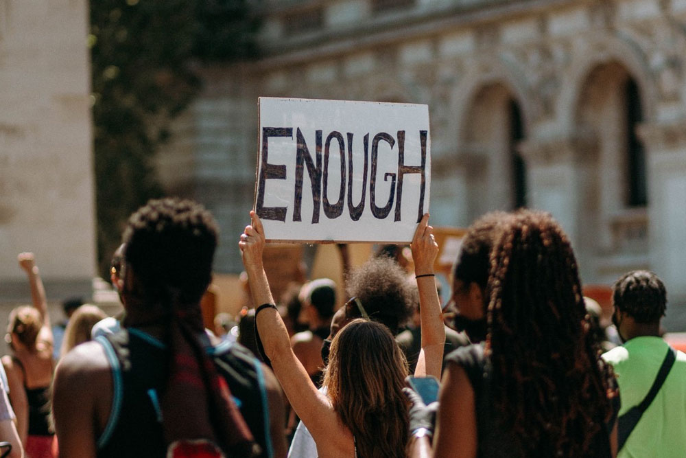 A woman holding a sign that reads 'Enough'