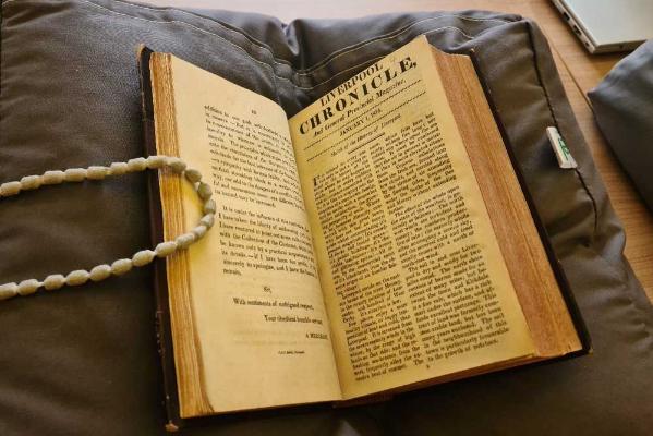 An antique book open at a page titled The Liverpool Chronicle
