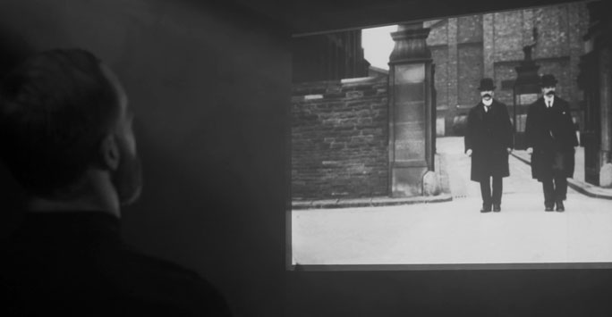 A man watching a black and white film in a dark room