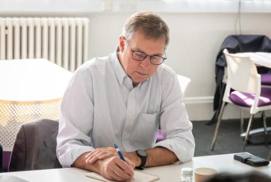 man writing notes on notepad