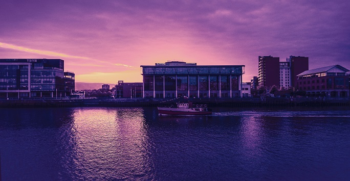 Belfast cityscape at sunset - the sky is purple and pink coloured, with the Titanic museum in the foreground 