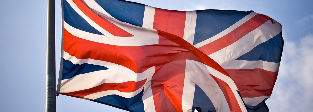 A Union Jack flag on a flagpole against a blue sky