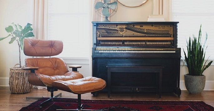 reclined leather chair next to a piano in a light room