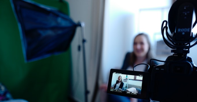 women being interviewed on camera, the recording screen of the camera is in focus with the interviewee blurred
