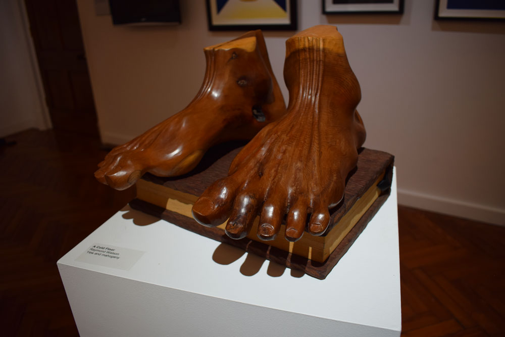 Wooden sculpture of two feet standing on a bible