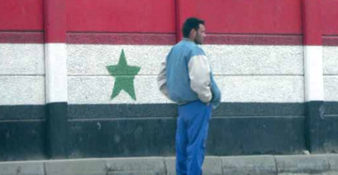 Man standing by a flag mural in Iraq