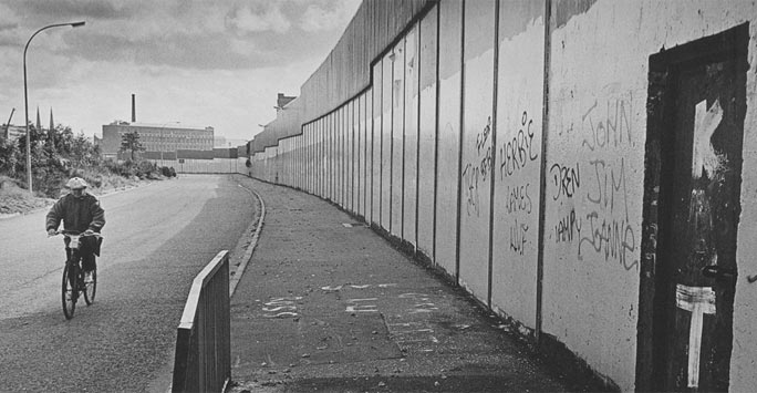 Man on bike next to a long barrier