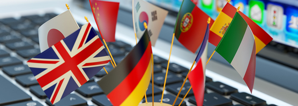 Mini flags of different countries resting on a laptop keyboard