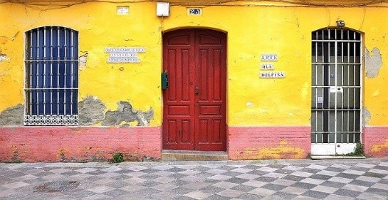traditional spanish building with yellow wall and red door