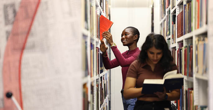 Student putting a book back on the shelf.