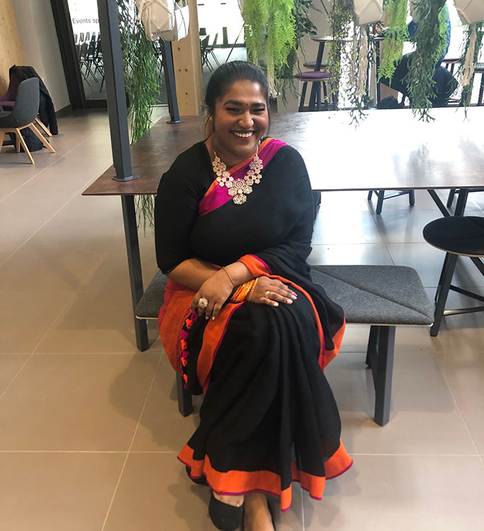 Laxmi sitting in the foyer of the School of Law and Social Justice