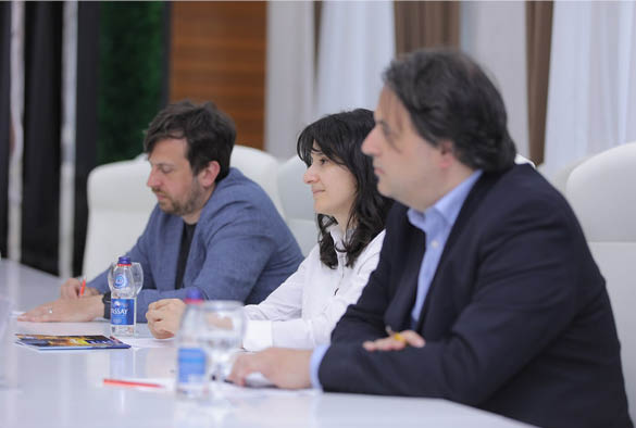 A photo of Valsamis, Kanstantsin, and Mavluda, sat at a table having a discussion.