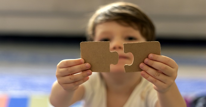 Child holding two jigsaw pieces