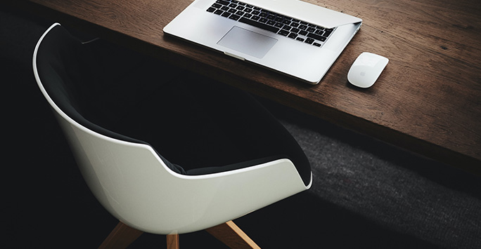 Photograph of a desk chair and laptop by Luca Bravo on Unsplash