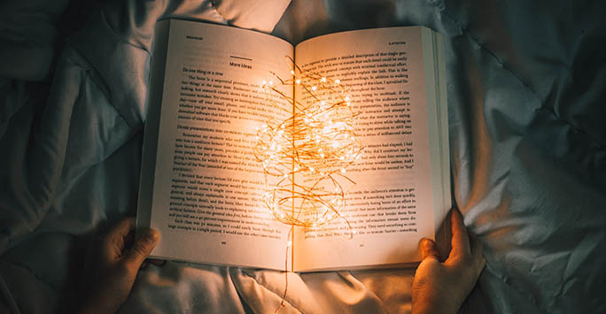 Unsplash photo of an open book of ideas, illuminated by fairy lights, by Nong Vang