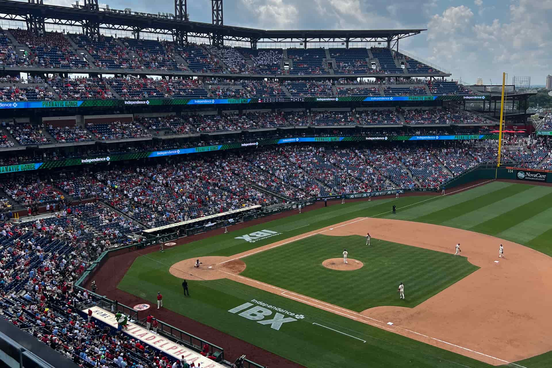 Elevated view of a baseball stadium during a live game, with players on the field and a large crowd in the stands.