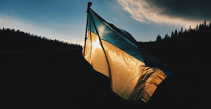Ukrainian flag with the sun setting behind it