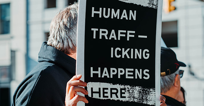 Protester holding sign 'human trafficking happens here'