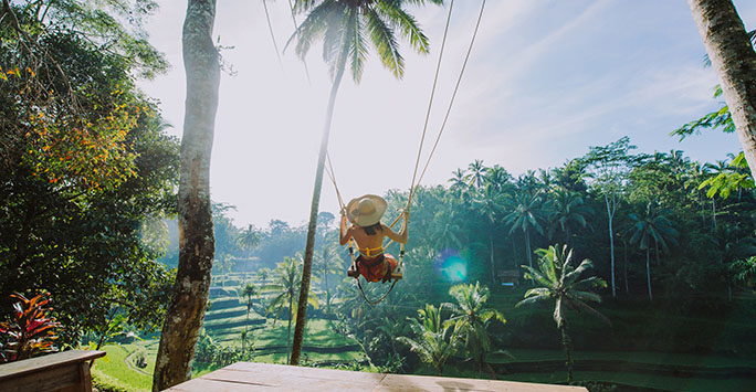 Woman on a swing overlooking the rice fields in Ubud, Bali