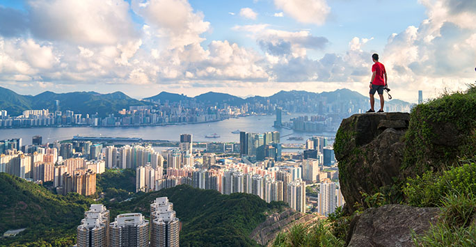 Photographer on cliff looking over Hong Kong city